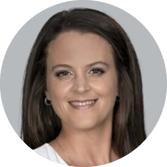 Portrait of Nurse Practitioner Ashley Comer, smiling with a light gray background.