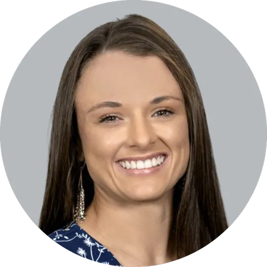 Portrait of Physician Assistant Danielle Molina wearing a blue suit and floral-patterned shirt, smiling with a light gray background
