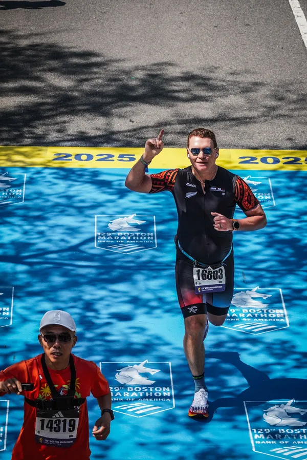 Dr. Timothy Deer pointing skyward at the 2025 Boston Marathon finish line