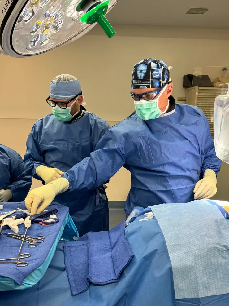 Dr. Timothy Deer and a colleague in surgical gowns and masks performing a procedure in the operating room
