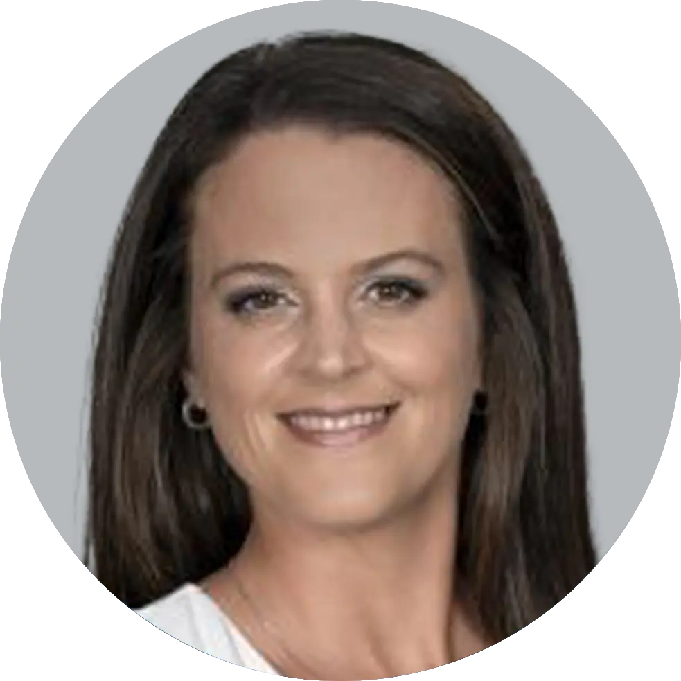 Portrait of Nurse Practitioner Ashley Comer, smiling with a light gray background.”
