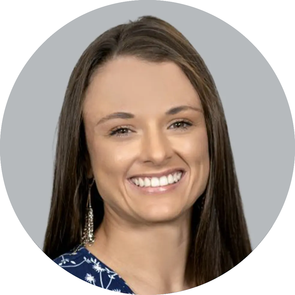 Portrait of Physician Assistant Danielle Molina wearing a blue suit and floral-patterned shirt, smiling with a light gray background